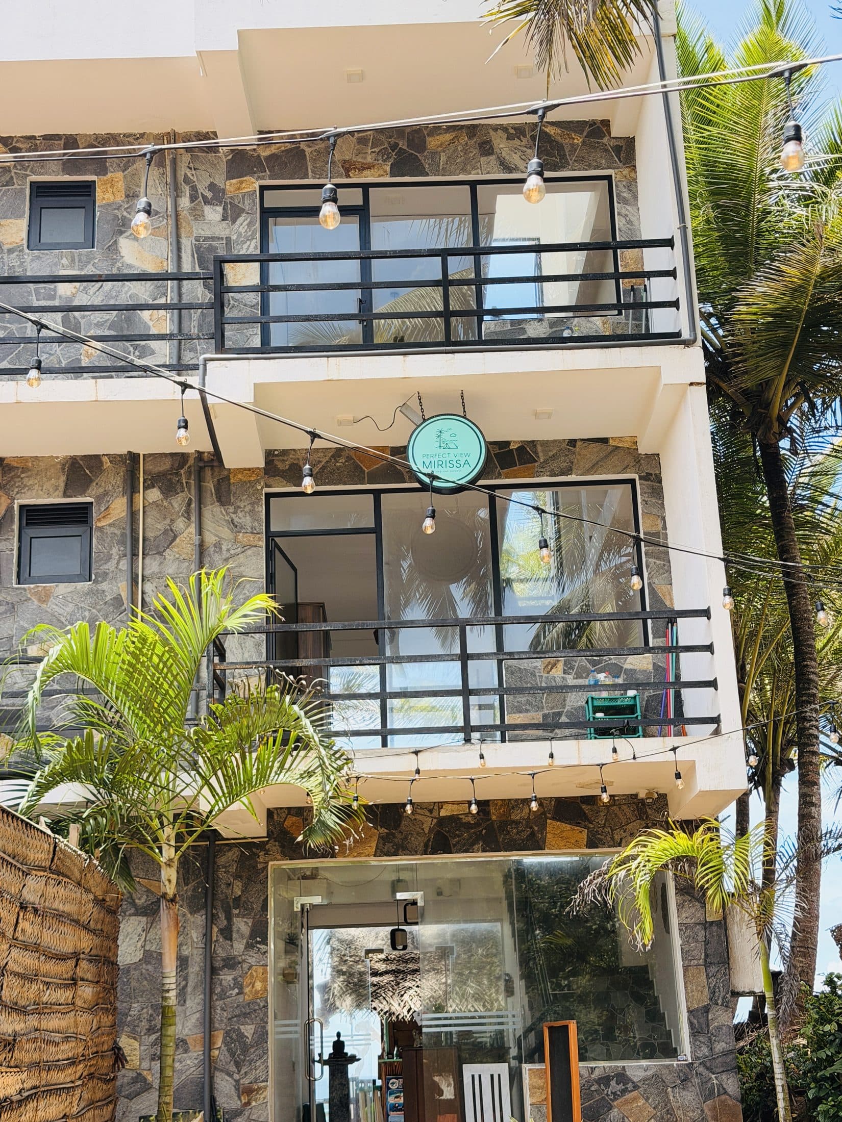 The front of Perfect View: stone-clad walls, balconies and the round logo sign