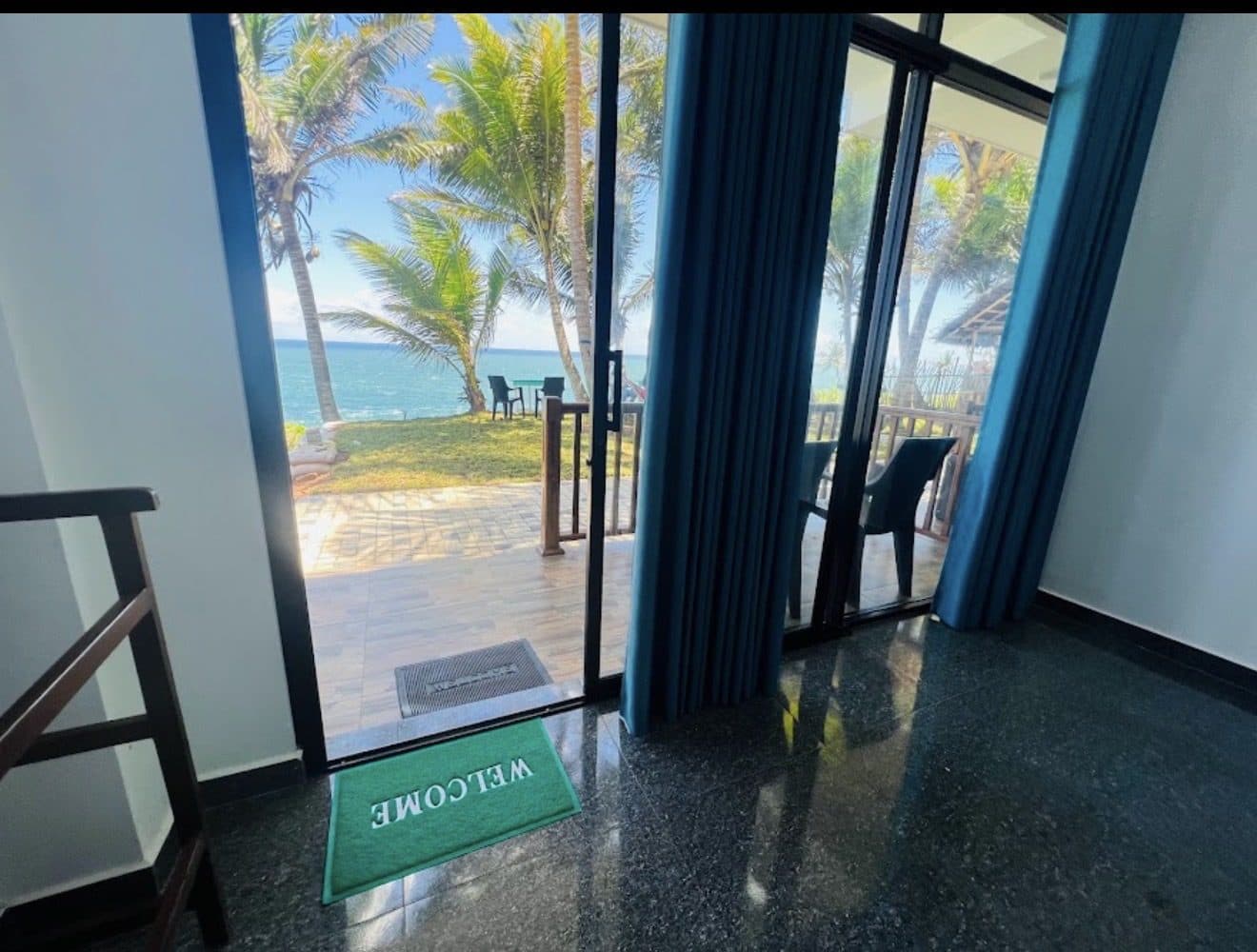Looking out of a room's glass doors to the lawn, the palms and the sea